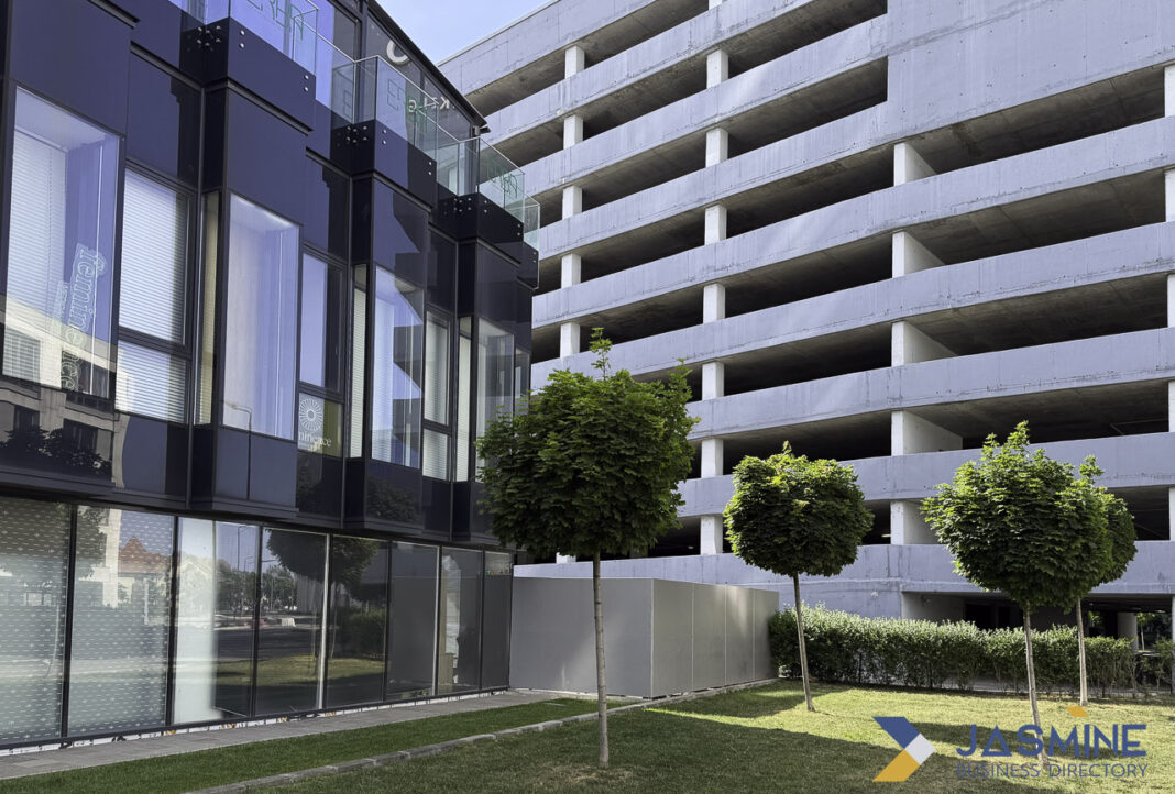 Modern professional building complex representing infrastructure for legal office directories and business services Modern office building with glass facade next to concrete parking structure with landscaped courtyard, illustrating professional infrastructure for legal directory services.
